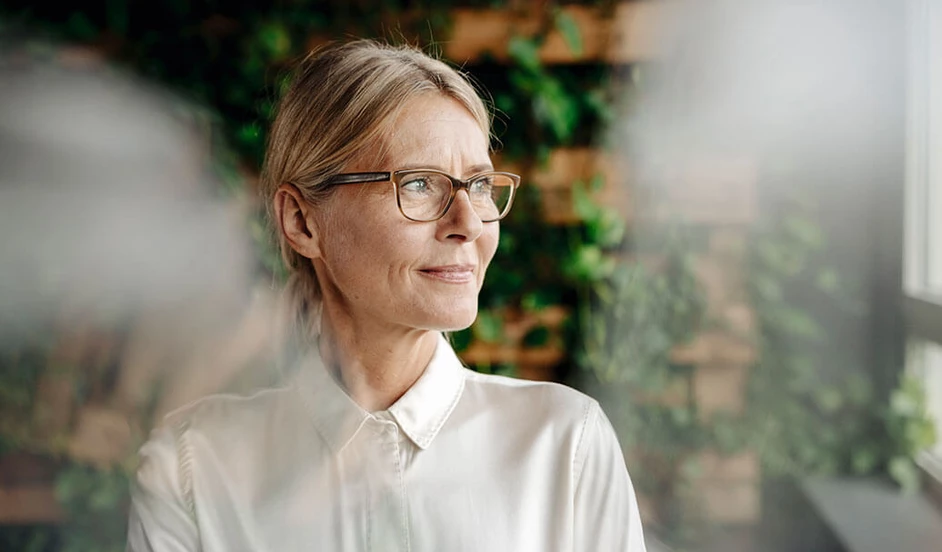Frau mit Brille schaut aus dem Fenster.