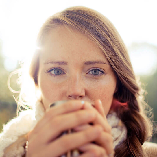 Portrait einer jungen Frau, die eine Teetasse in beiden Händen holt