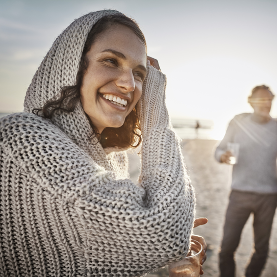 Frau mit Strickkaputze am Strand