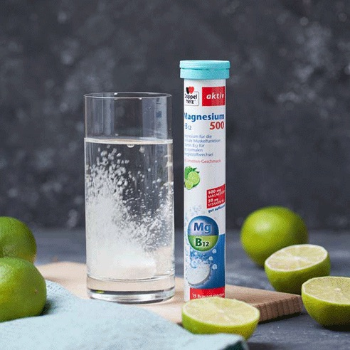 Doppelherz Magnesium 500 + B12 neben Limetten und Glas mit Brausetablette