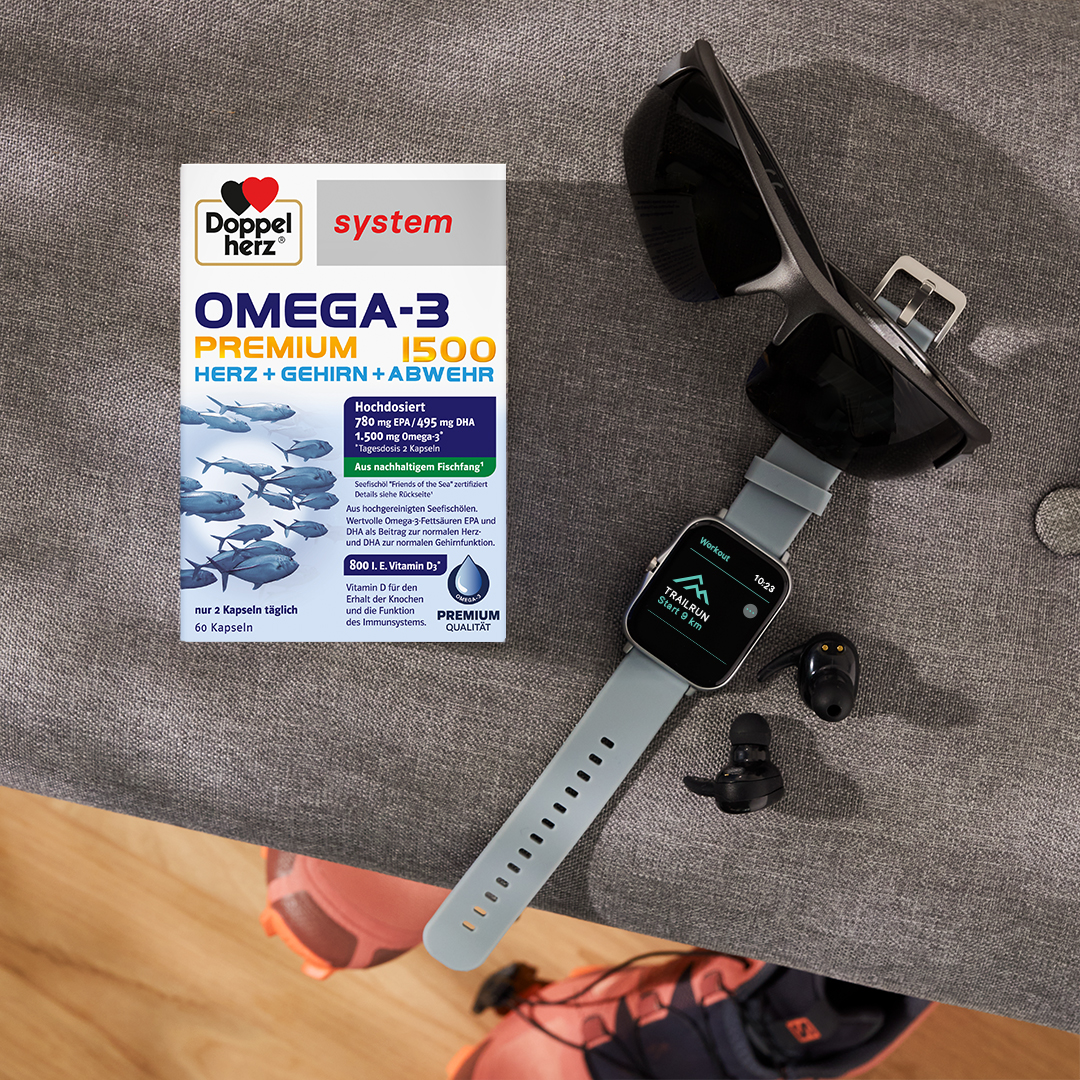 Doppelherz system Omega-3-Premium Produkt neben einer Fitnessuhr
