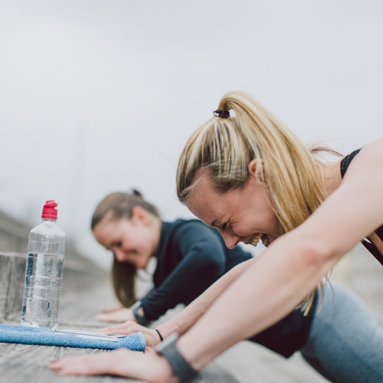 Zwei Frauen machen zusammen Liegestütze