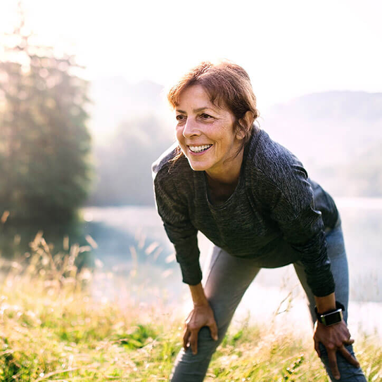 Ältere Frau pausiert nach Sport in der Natur an einem nebligen Morgen