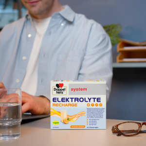 Doppelherz system Elektrolyte Recharge auf Schreibtisch, Mann arbeitet im Hintergrund