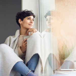 Entspannte Frau sitzt zu Hause am Fenster