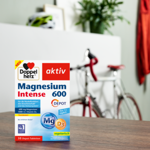 Doppelherz Magnesium 600 Intense auf Tisch mit Fahrrad im Hintergrund