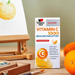 Doppelherz system Vitamin C 1000 Brausetabletten auf Tisch neben Staffelei und Orangen