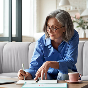 Glückliche stilvolle alte Frau im Homeoffice an ihrem Laptop