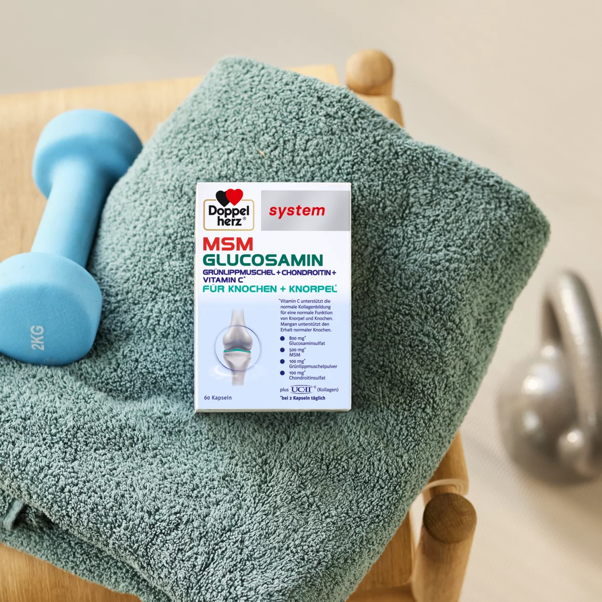 Doppelherz system MSM Glucosamin auf Handtuch neben Hantel