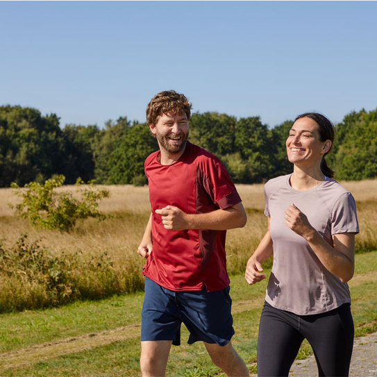 Glückliches Paar joggt an einem Getreidefeld vorbei