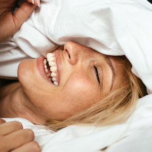 Junge Frau wacht mit einem lächeln im Bett auf 