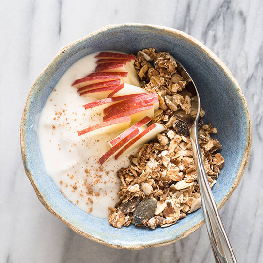 Schale mit Muesli, Apfelscheiben und Joghurt